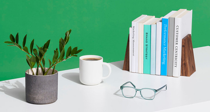 Desk with potted plant, coffee mug, spectacles and marketing books